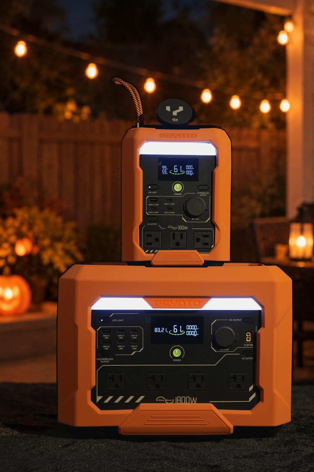 Two orange GEYOTO power stations stacked together under string lights in a Halloween-themed setting.