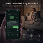A hand holds a smartphone showing a charging and status app screen in the foreground, while a woman wrapped in a blanket sits on a couch in the background. Text at the top reads 'Stay Connected.