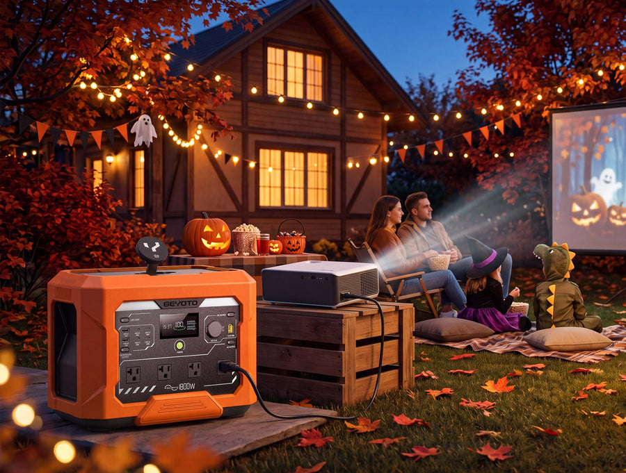 Orange GEYOTO power station beside a projector during a Halloween movie night in a decorated backyard.